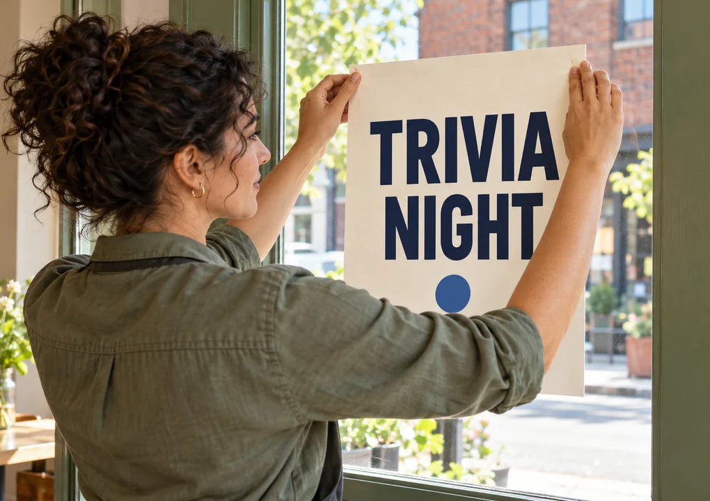 Fictional bar manager attaching a simple Trivia Night poster to entrance glass