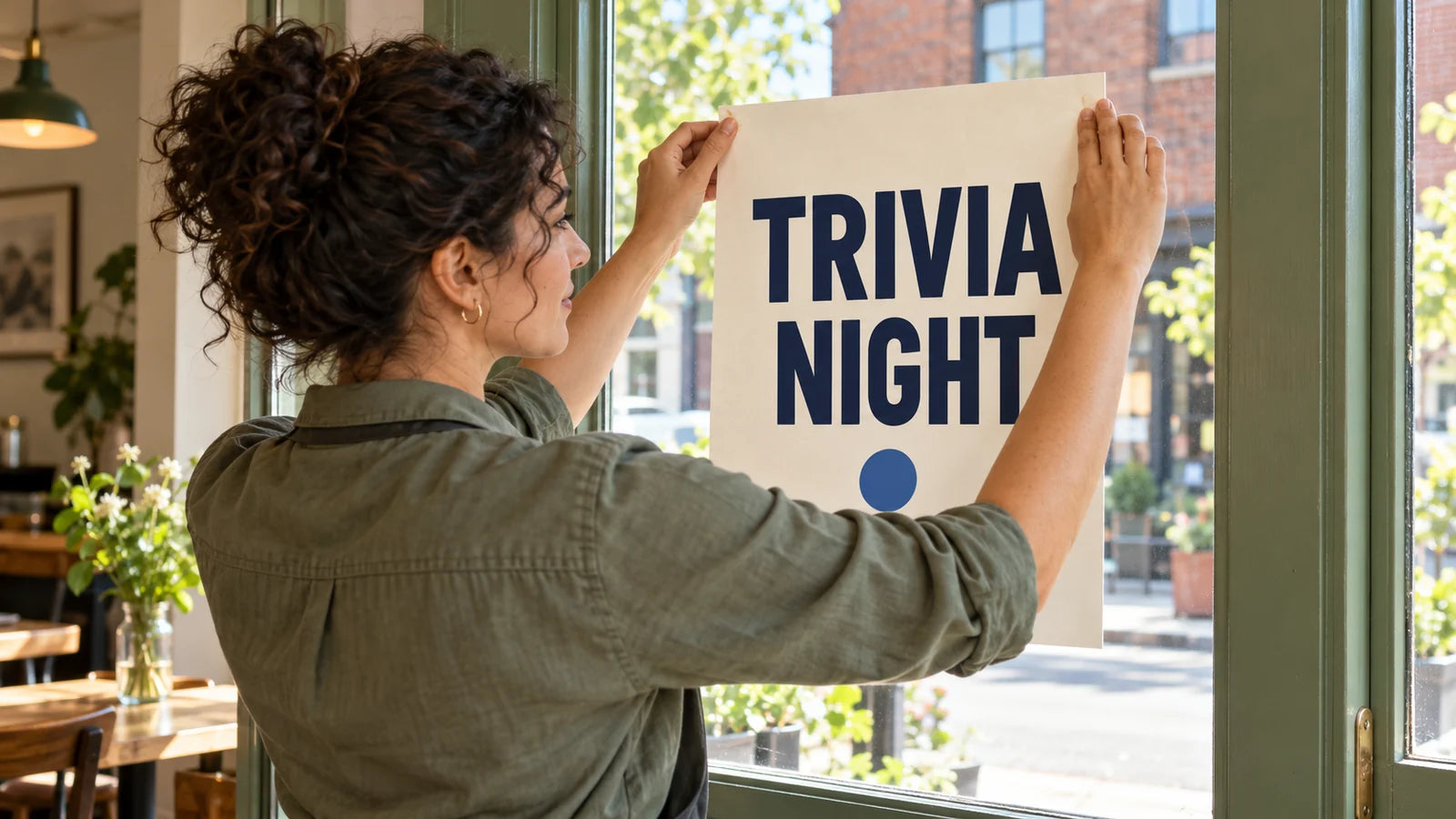 Fictional bar manager attaching a simple Trivia Night poster to entrance glass