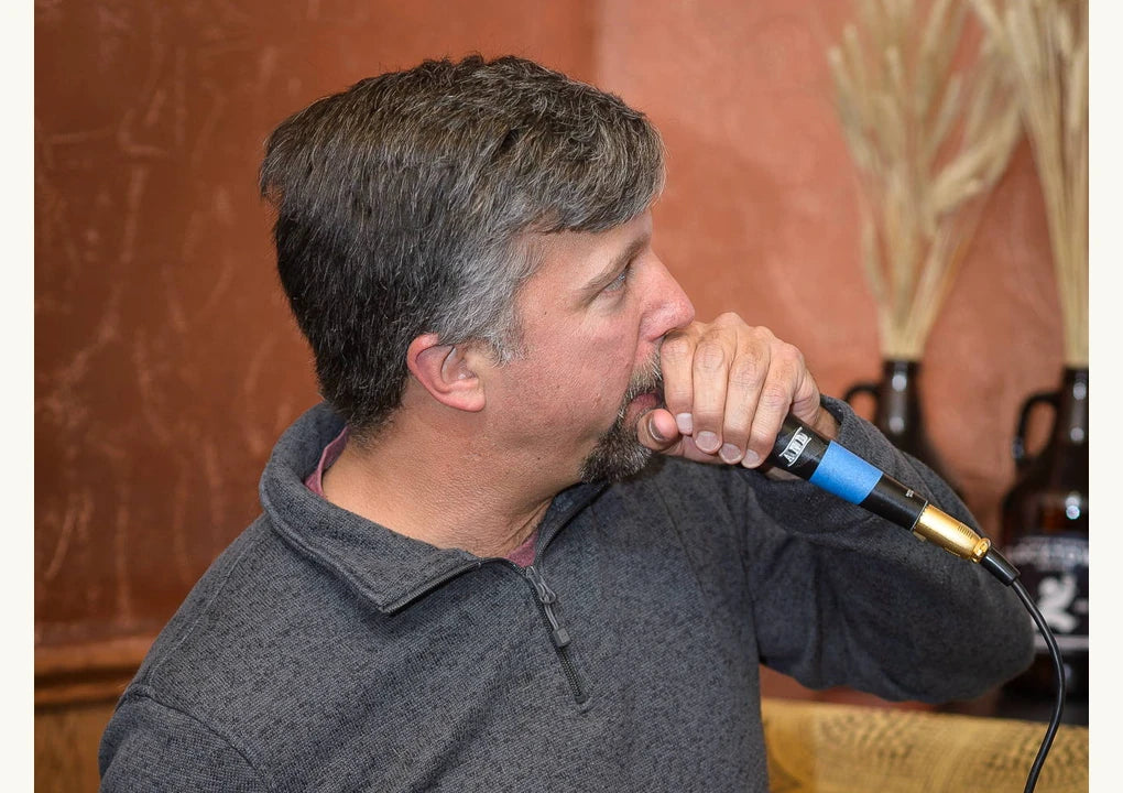 Quiz host speaking into a microphone in a photograph from the original fundraiser guide