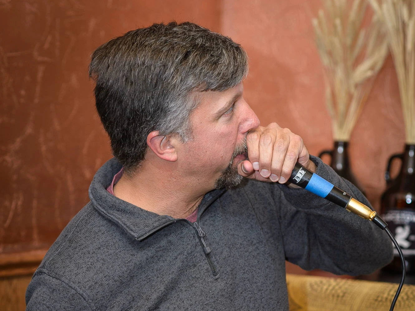 Quiz host speaking into a microphone in a photograph from the original fundraiser guide